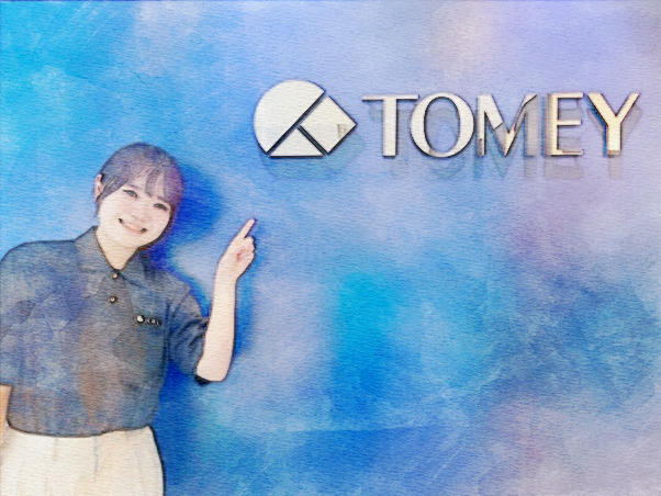TOMEYの製造部スタッフがロゴを指しながら、製品の製造について説明している。