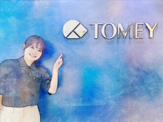 TOMEYの製造部の社員がロゴを指しながら、製品の製造について説明している